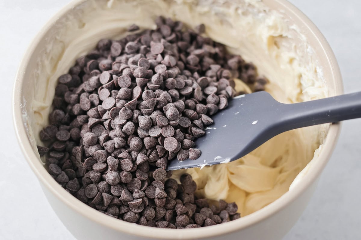 Using a spatula to fold in mini chocolate chips into the the dip.