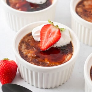Chocolate creme brûlée in ramekins with strawberry on top.