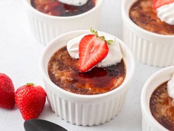 Chocolate creme brรปlรฉe in ramekins with strawberry on top.