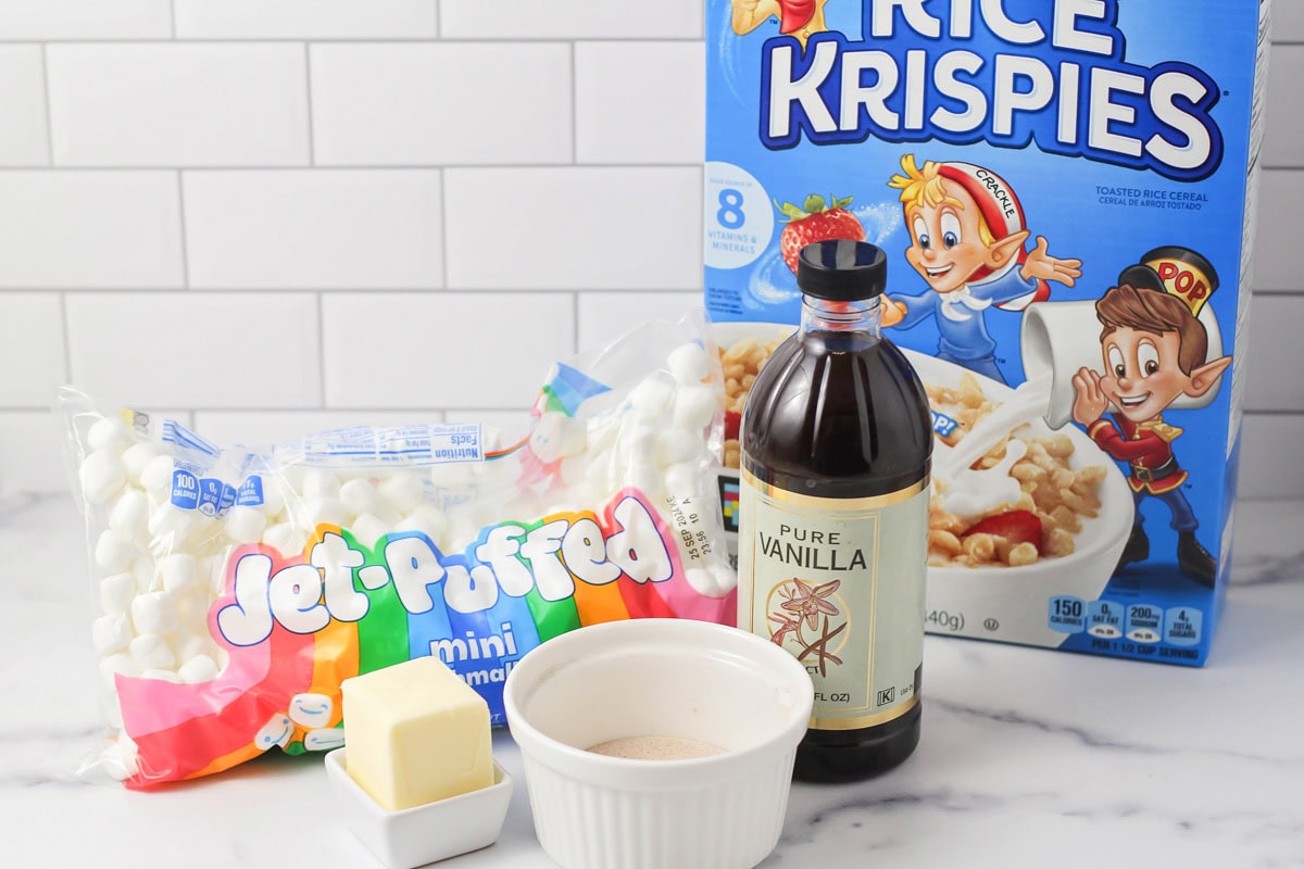 These no bake churro Rice Krispie treats showcase extra marshmallows and a cinnamon sugar topping for sweet, soft, and cozy bites. Ingredients to make churro Rice Krispie treats on a kitchen counter,