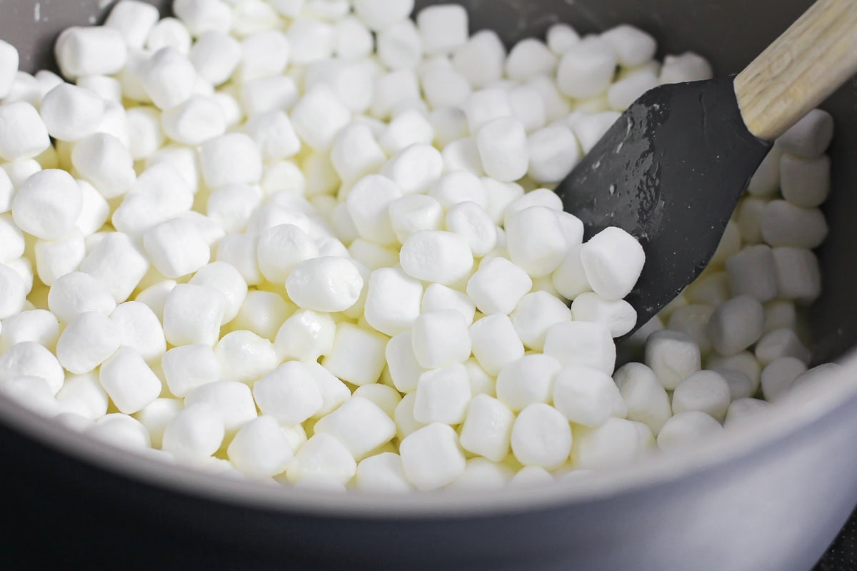 These no bake churro Rice Krispie treats showcase extra marshmallows and a cinnamon sugar topping for sweet, soft, and cozy bites. Melted butter and mini marshmallows in pot.