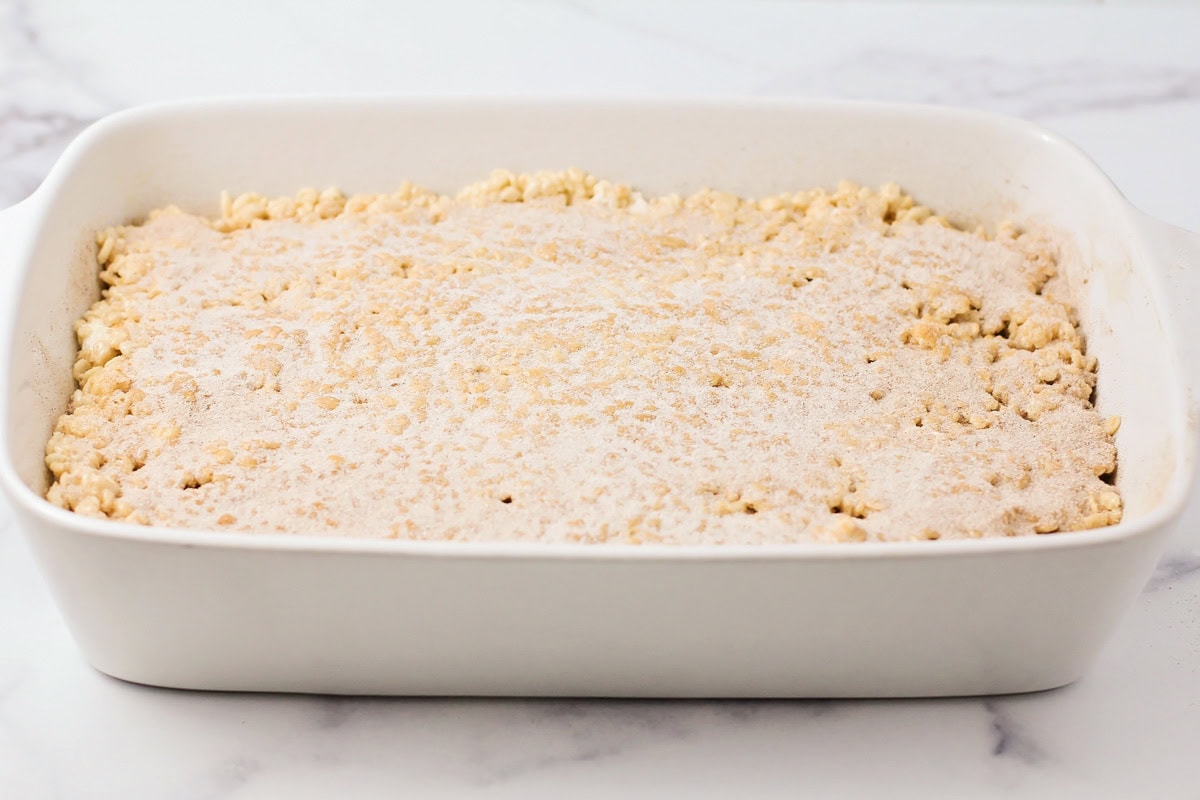 These no bake churro Rice Krispie treats showcase extra marshmallows and a cinnamon sugar topping for sweet, soft, and cozy bites. Cinnamon sugar sprinkles over a pan of Rice Krispie treats.