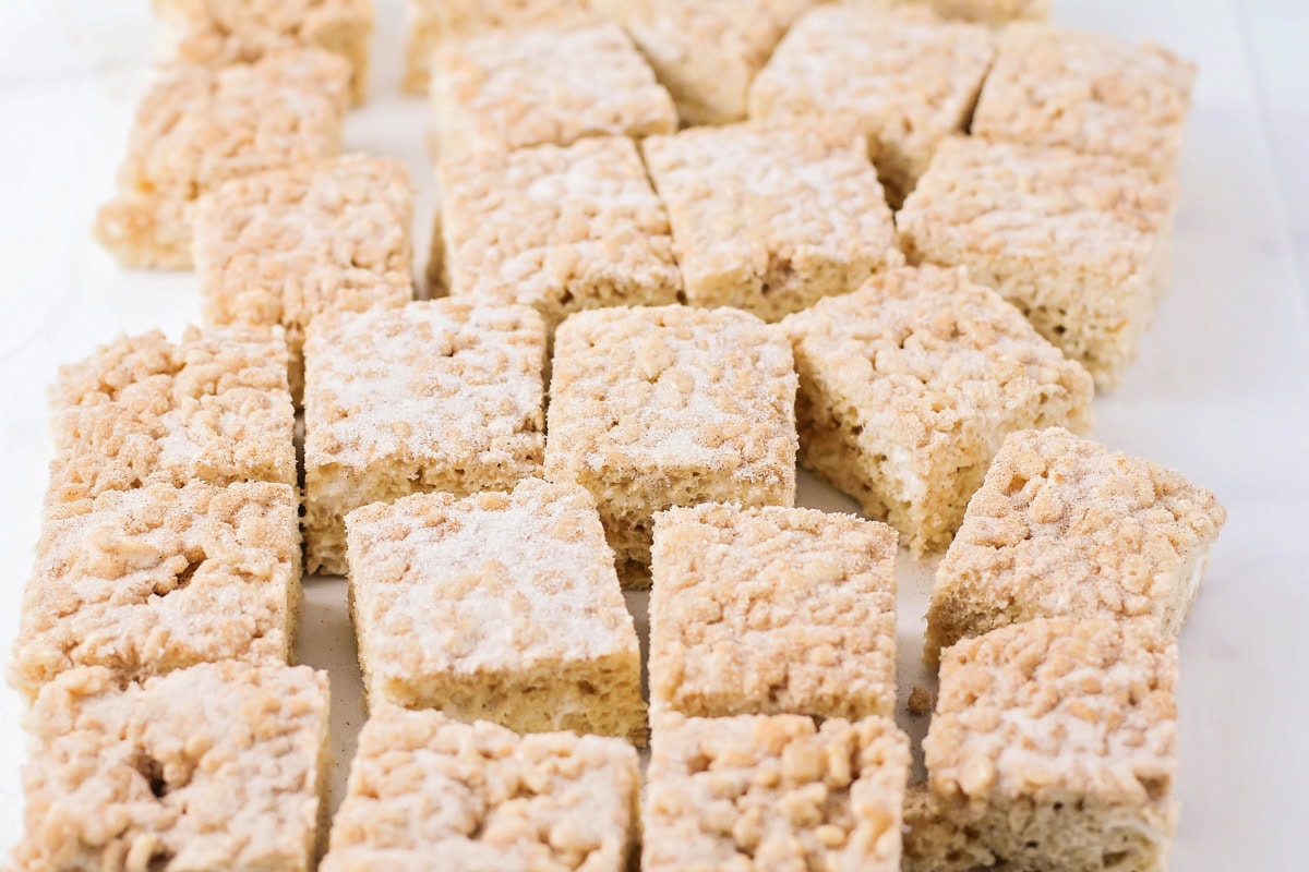 These no bake churro Rice Krispie treats showcase extra marshmallows and a cinnamon sugar topping for sweet, soft, and cozy bites. Several cut squares of churro Rice Krispie treats.