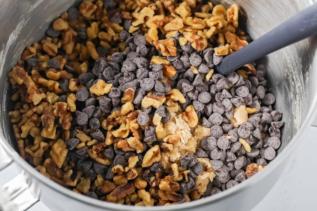 Copycat Doubletree cookies are big, chewy, and baked soft in the center with crisp edges for the ultimate treat. Walnuts and chocolate chips added to a mixing bowl with cookie dough.