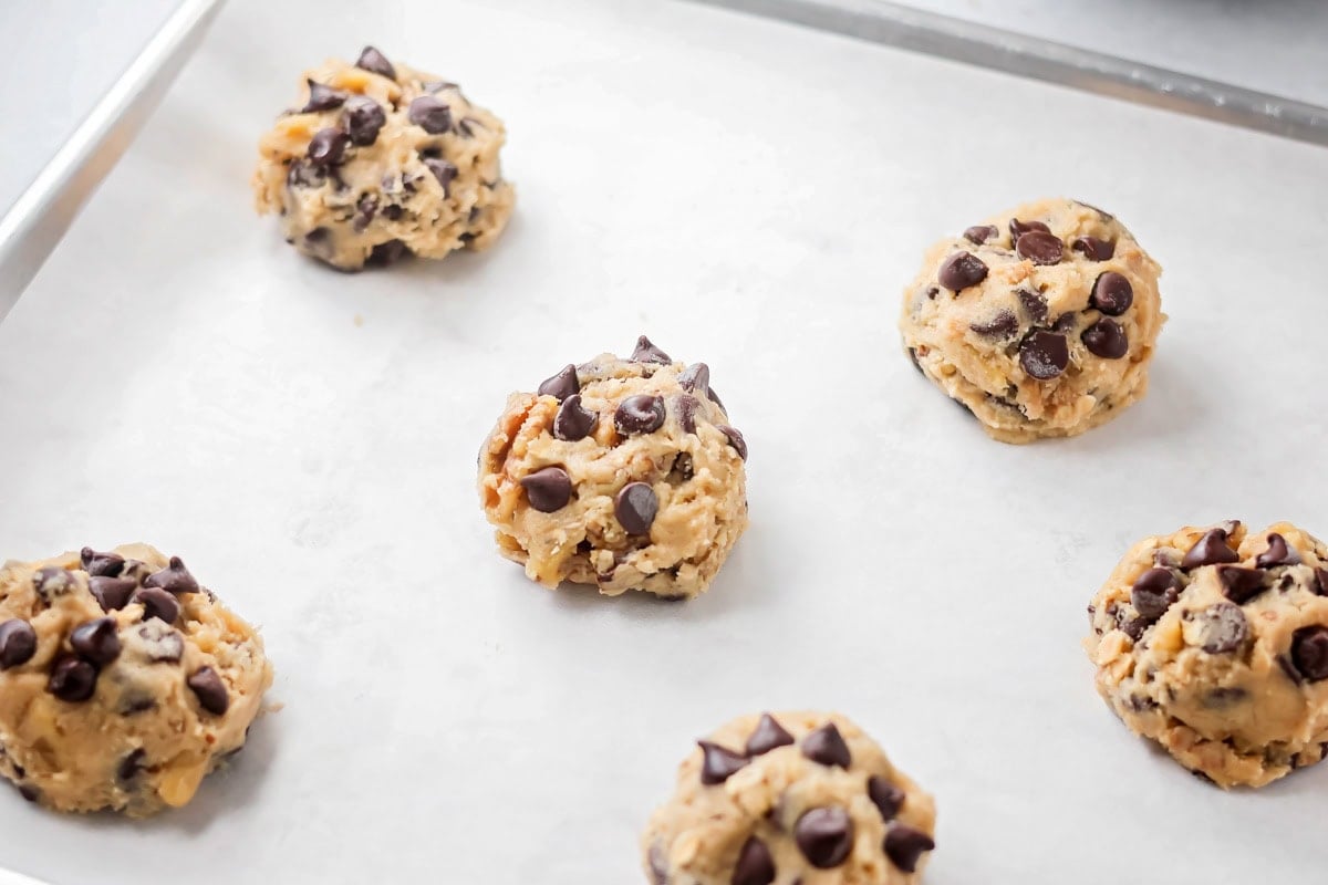 Copycat Doubletree cookies are big, chewy, and baked soft in the center with crisp edges for the ultimate treat. Chocolate chips added to the tops of cookie dough balls.