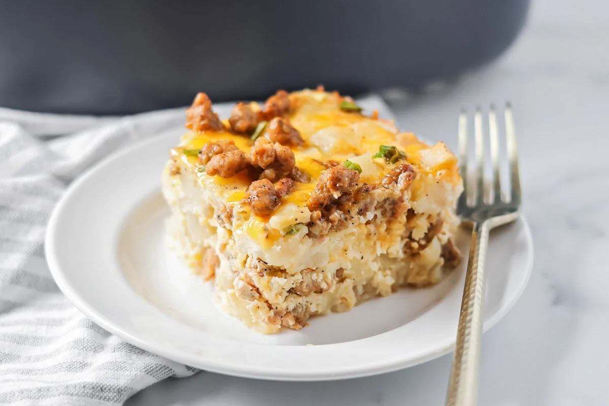 Crockpot breakfast casserole layers favorite breakfast foods for an easy and cozy dish that feeds a crowd with almost no effort. A slice of crockpot breakfast casserole on a serving plate.