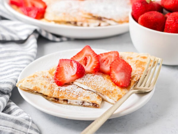 Dessert quesadillas on plate with sliced strawberries on top.