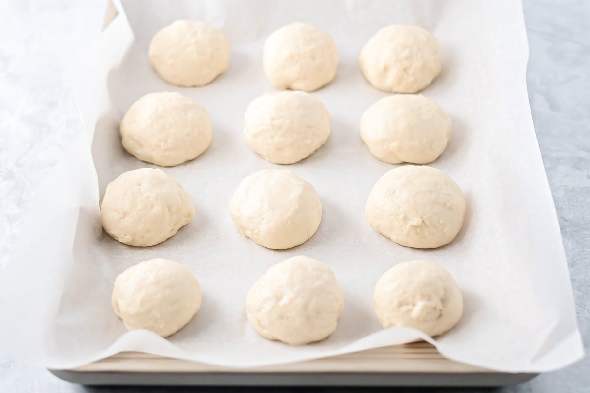 With just 4 ingredients, these easy yeast rolls are ready in under an hour and are perfect for a light snack or served with dinner. Twelve dough balls in a parchment lined baking pan.