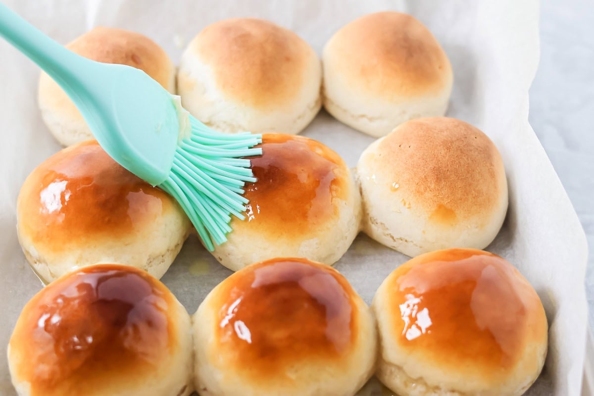 With just 4 ingredients, these easy yeast rolls are ready in under an hour and are perfect for a light snack or served with dinner. Brushing on butter to baked dinner rolls.