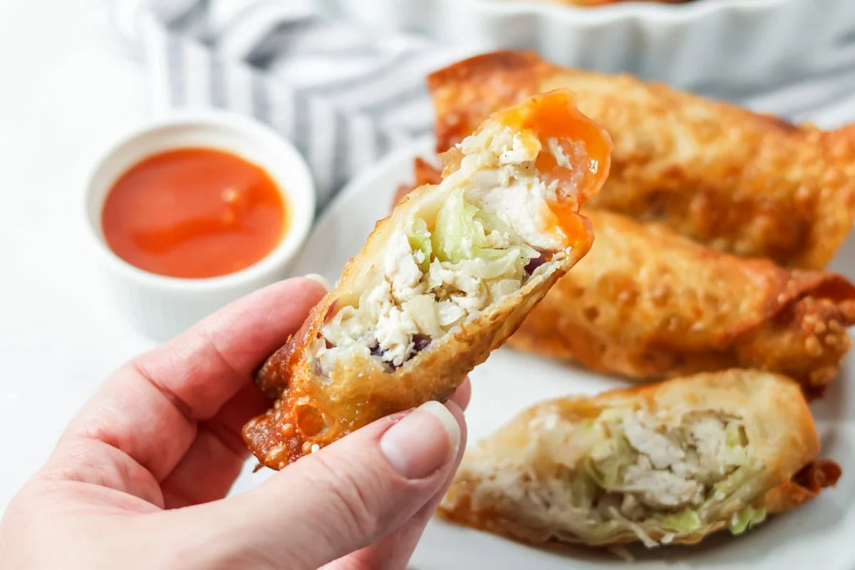 Holding half an egg roll thats been dipped in sauce.