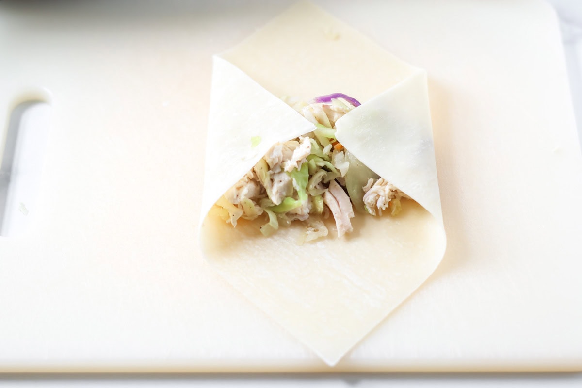 The left and right corners of the egg roll folded over the filling.