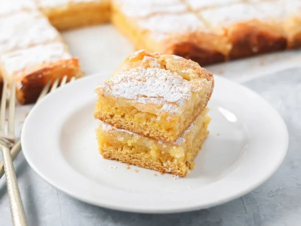 Two slices of gooey butter cake stacked on a white plate.