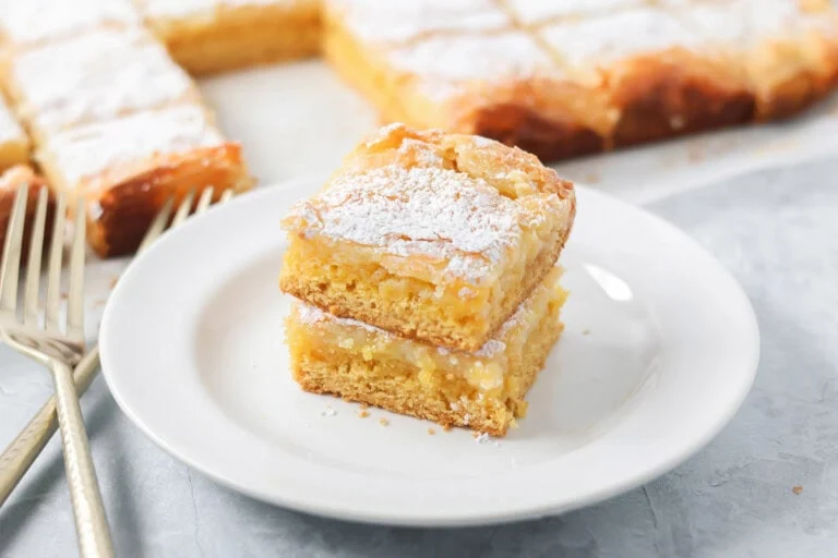 Two slices of gooey butter cake stacked on a white plate.