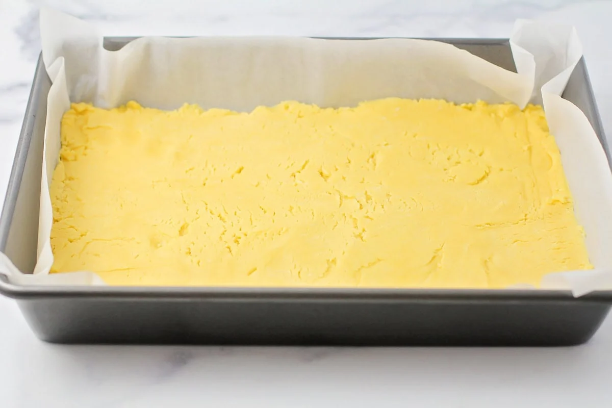 Cake batter pressed into a parchment lined baking pan.