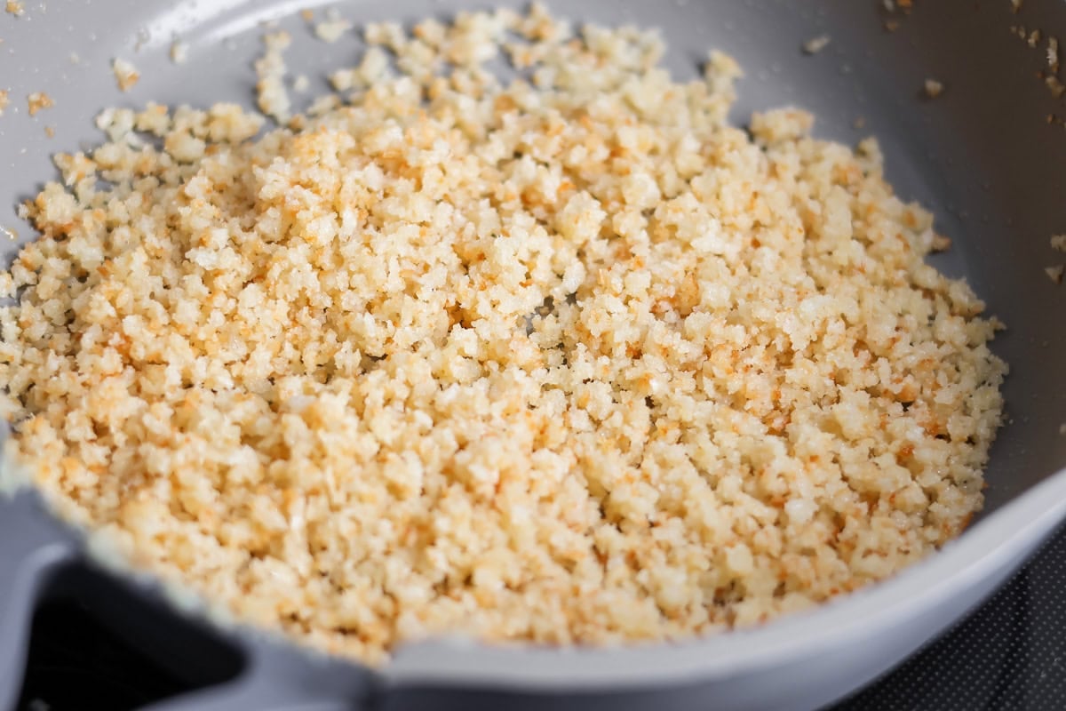 Panko topping being cooked in skillet.