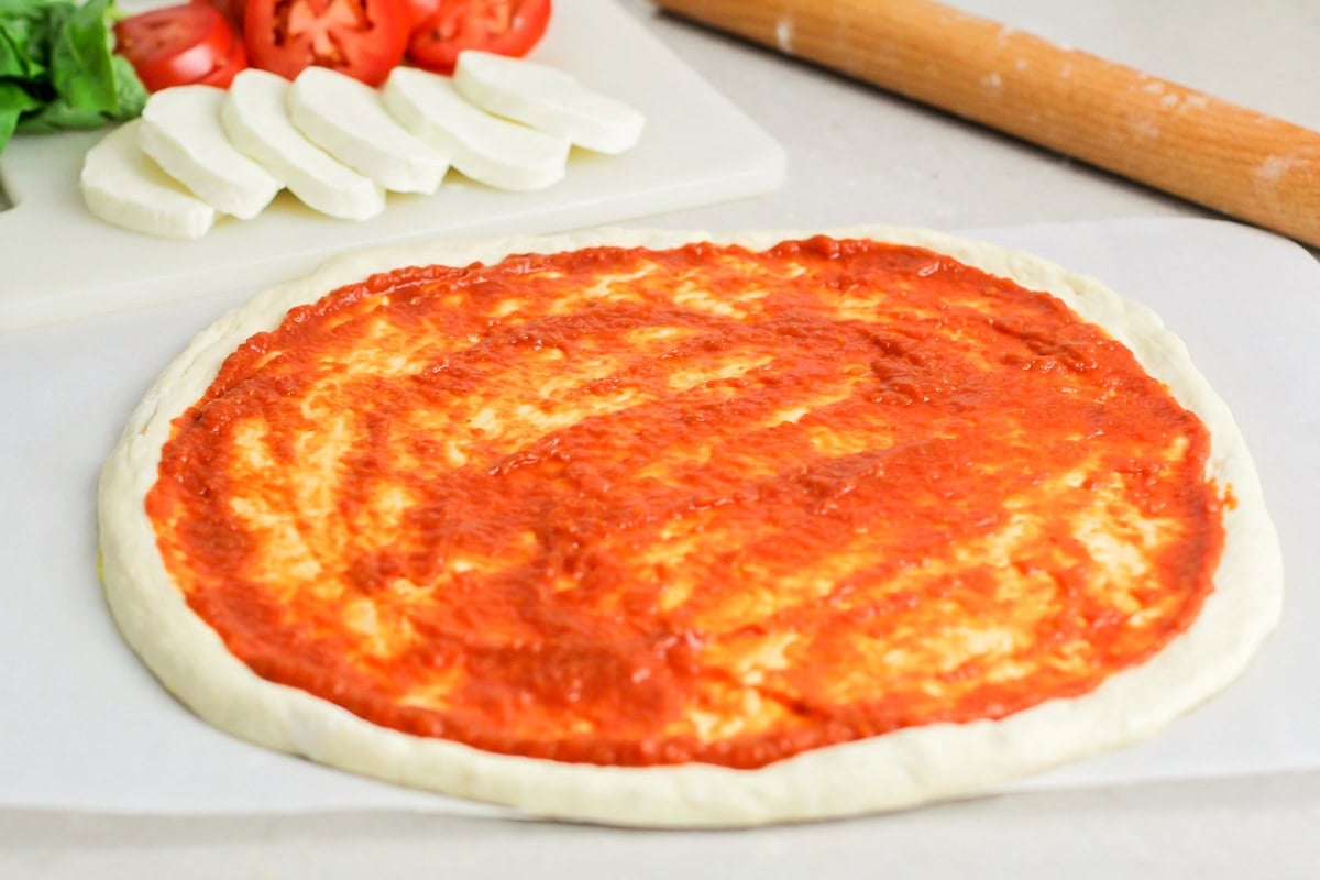 Margherita pizza stars fresh basil, mozzarella cheese, and the best ripe tomatoes. It's simple, delicious, and light. Pizza sauce slathered on pizza dough.
