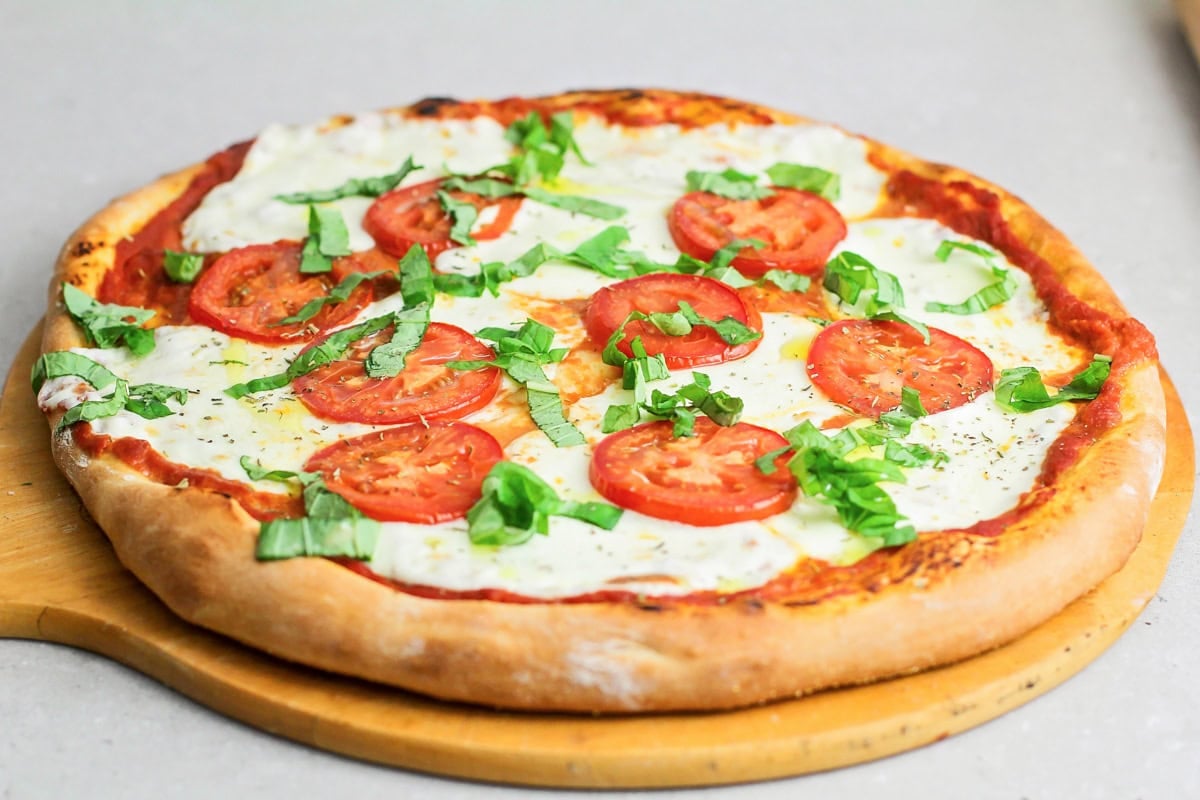 Margherita pizza stars fresh basil, mozzarella cheese, and the best ripe tomatoes. It's simple, delicious, and light. Baked margherita pizza with fresh basil on top.