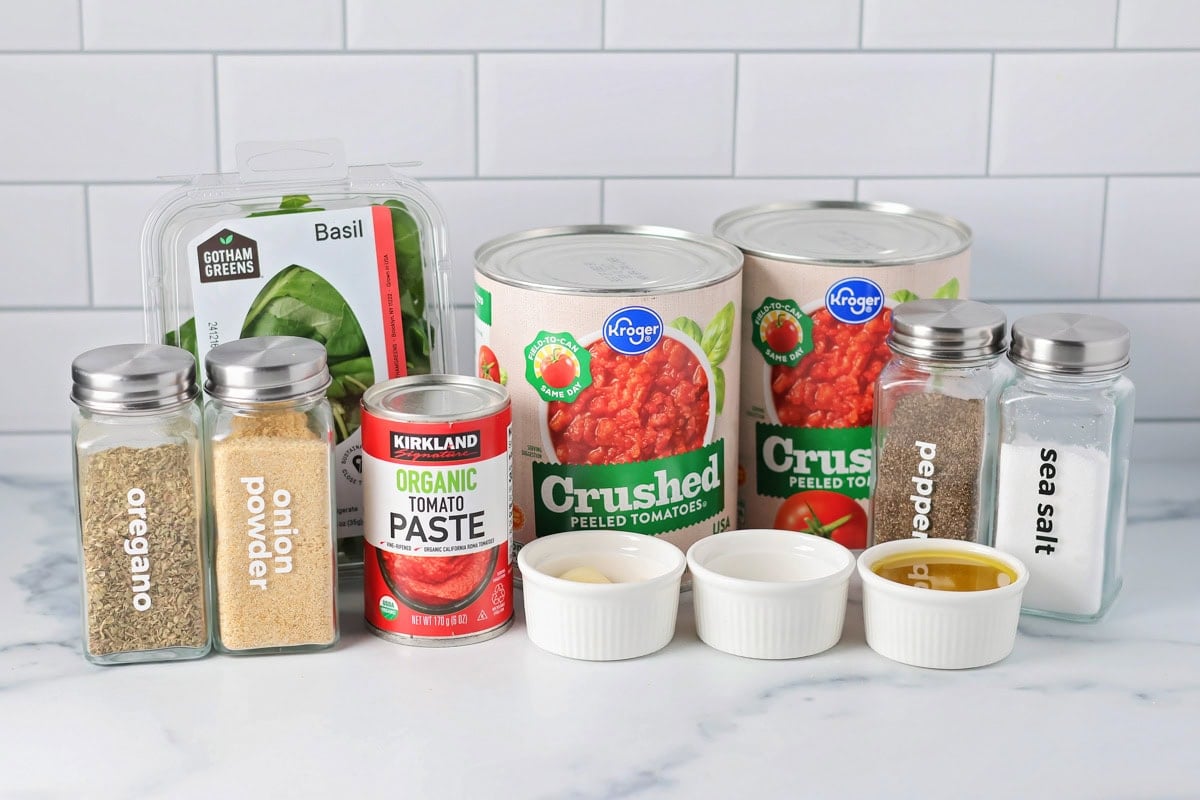 This simple homemade marinara sauce simmers fresh tomatoes with fragrant herbs and garlic for a versatile flavor explosion. Homemade marinara sauce ingredients on a kitchen counter.