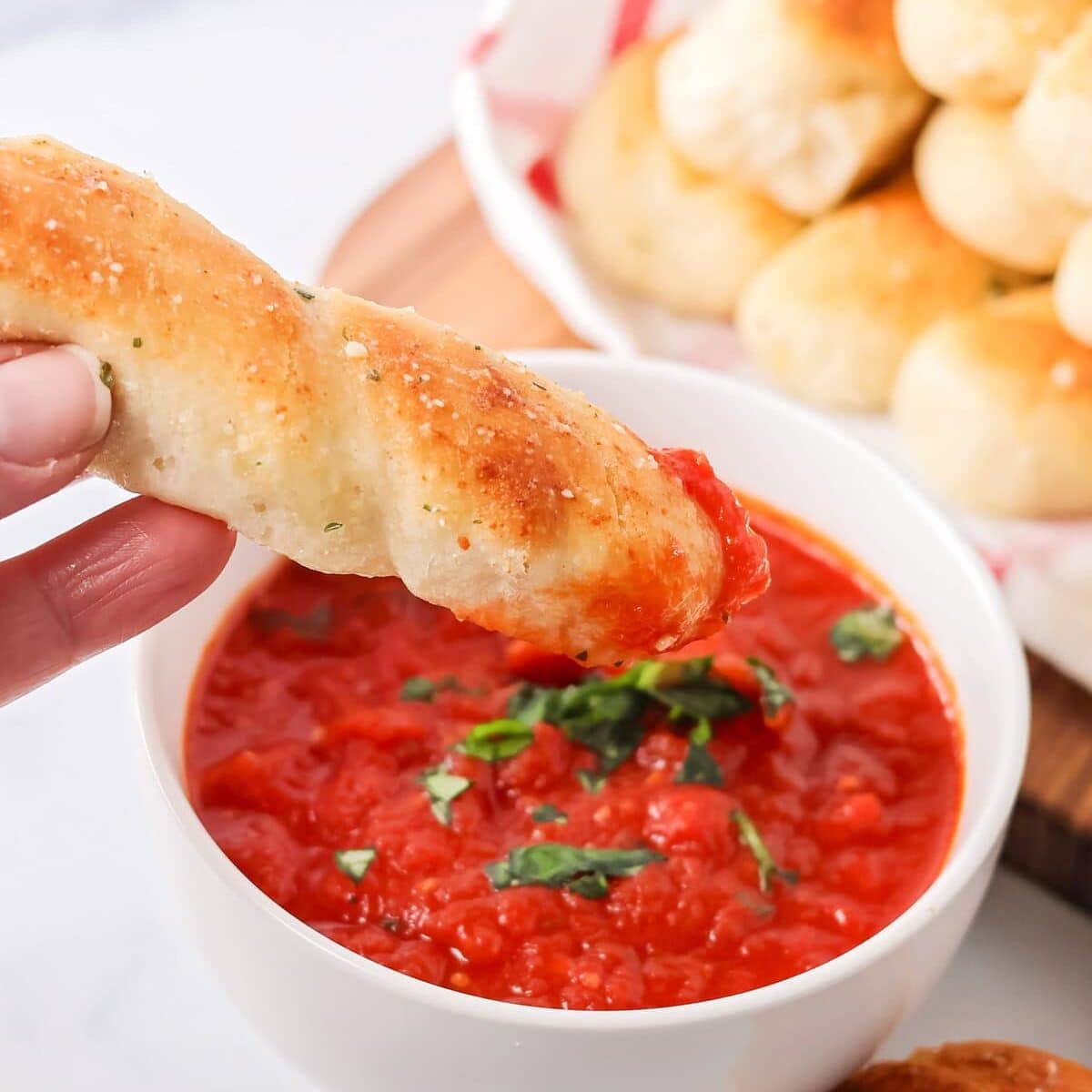 This simple homemade marinara sauce simmers fresh tomatoes with fragrant herbs and garlic for a versatile flavor explosion. Dipping a breadstick into marinara sauce.