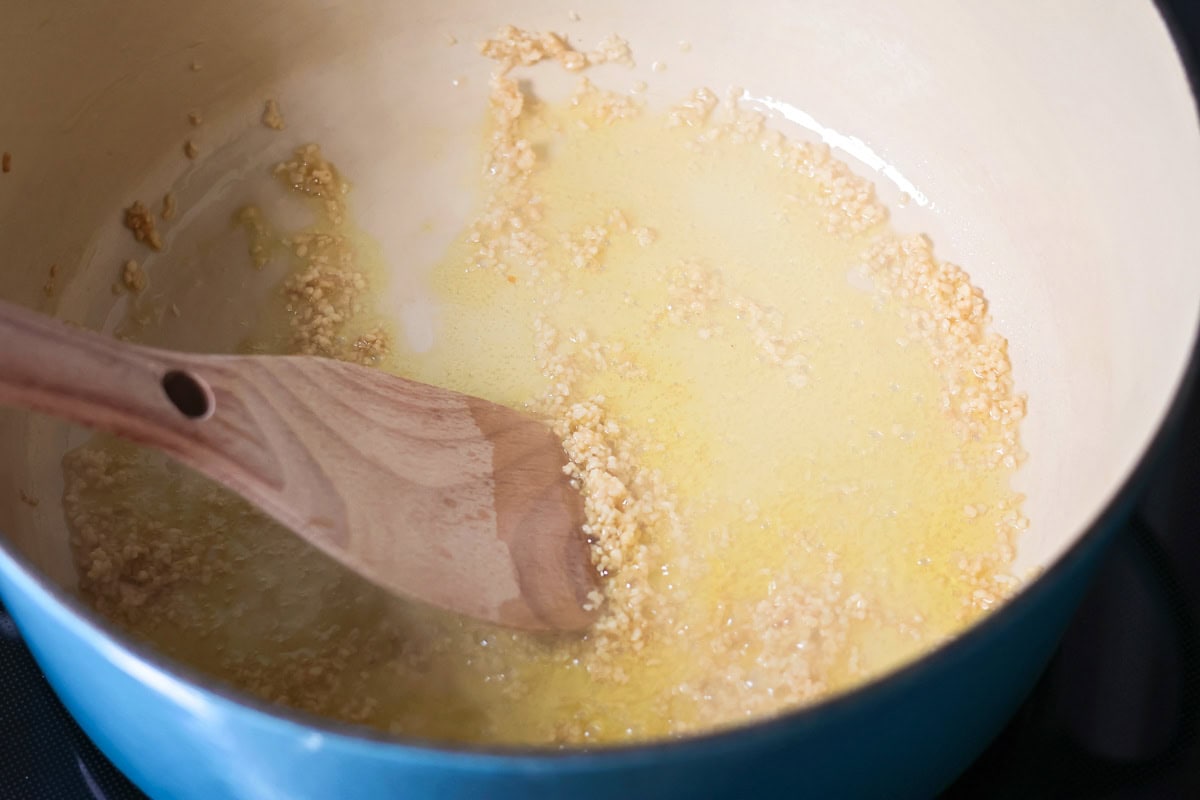 This simple homemade marinara sauce simmers fresh tomatoes with fragrant herbs and garlic for a versatile flavor explosion. Sauteing garlic in butter in a saucepot.