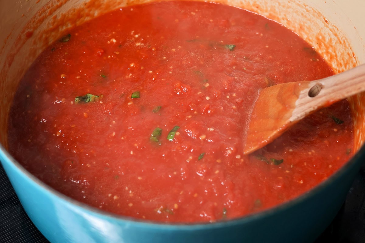 This simple homemade marinara sauce simmers fresh tomatoes with fragrant herbs and garlic for a versatile flavor explosion. Simmering marinara sauce in a pot.