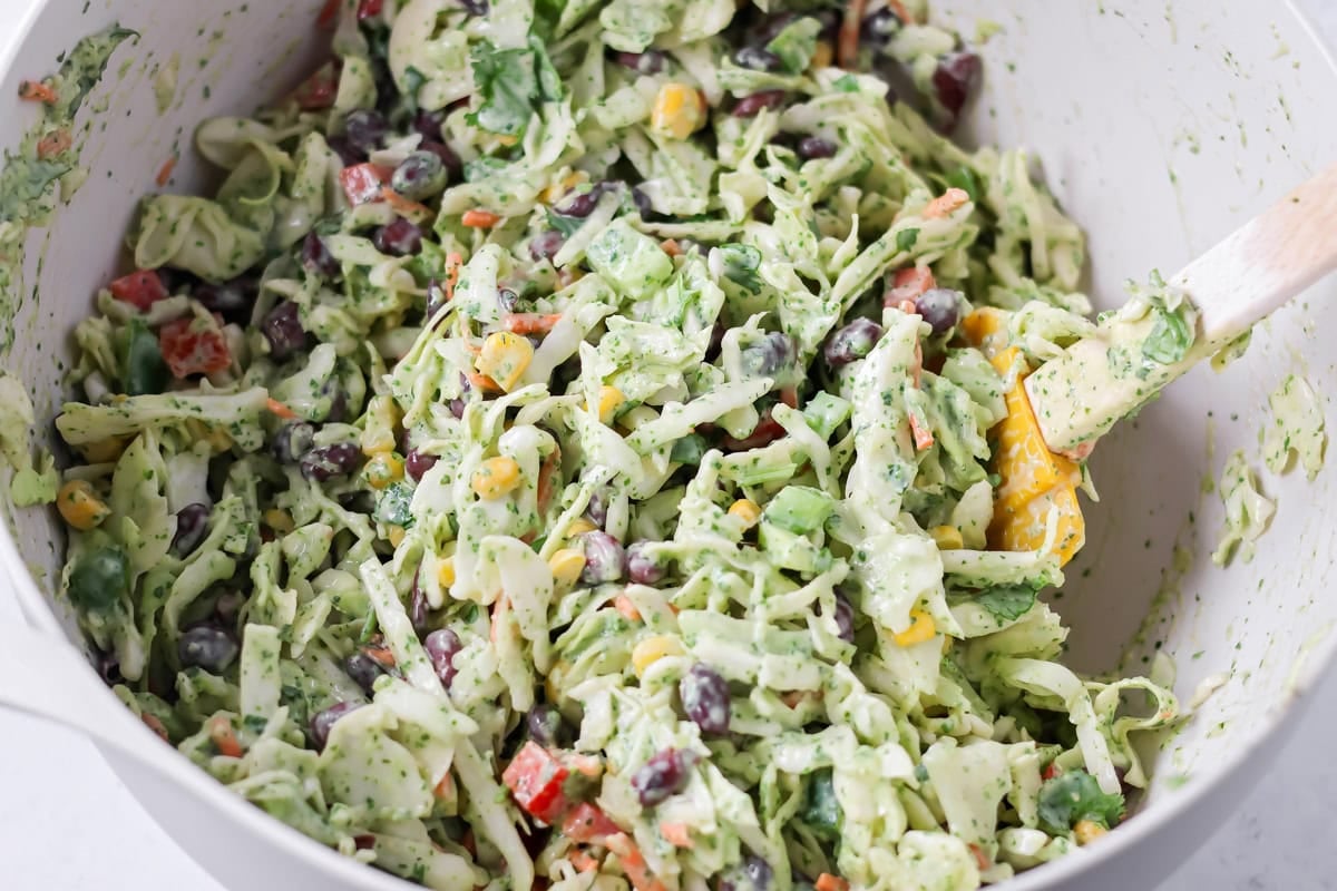 Mexican coleslaw ingredients mixed together in mixing bowl.