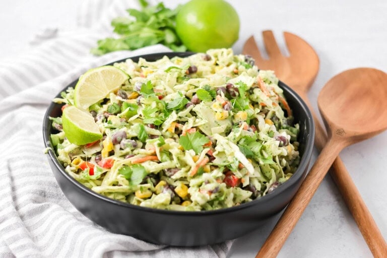 Mexican coleslaw recipe in black bowl with ingredients on the side.