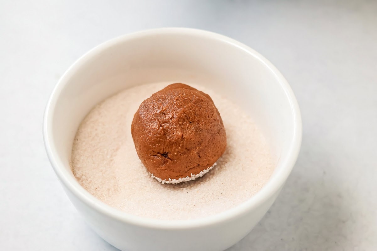 Easy Mexican hot chocolate cookies are soft and chocolatey with cinnamon sugar sparkle and a hint of heat, and perfect for sharing. Rolling a cookie dough ball in cinnamon and sugar.