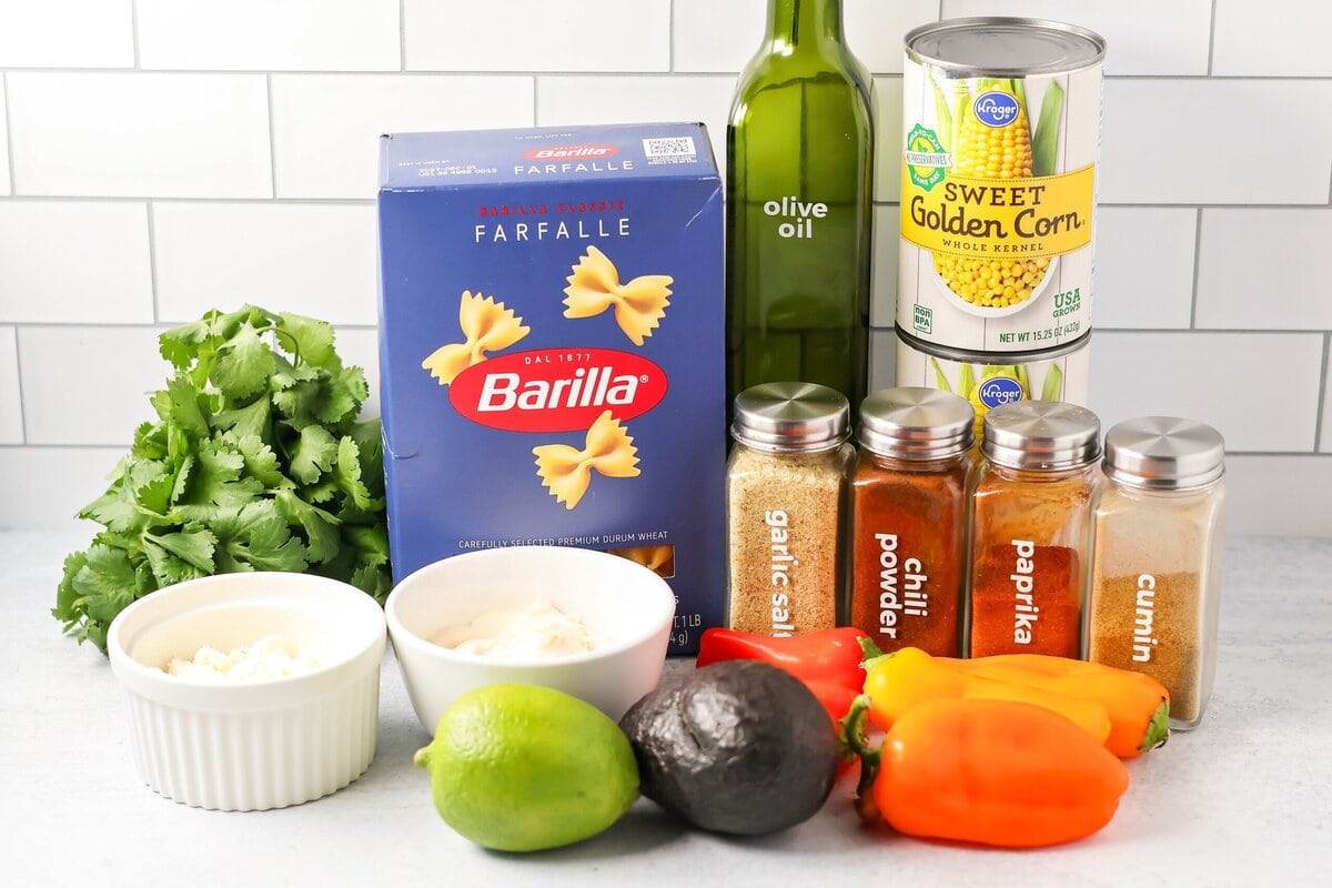 Creamy Mexican street corn pasta salad is a perfect balance of flavor, quick to toss together, and perfect for parties and easy dinners. Ingredients to make Mexican Street corn pasta salad on a kitchen counter.