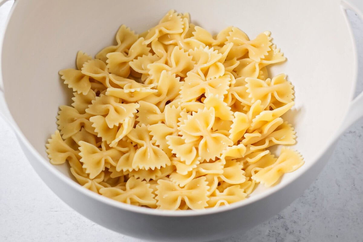 Creamy Mexican street corn pasta salad is a perfect balance of flavor, quick to toss together, and perfect for parties and easy dinners. Cooked bow tie pasta in a mixing bowl.