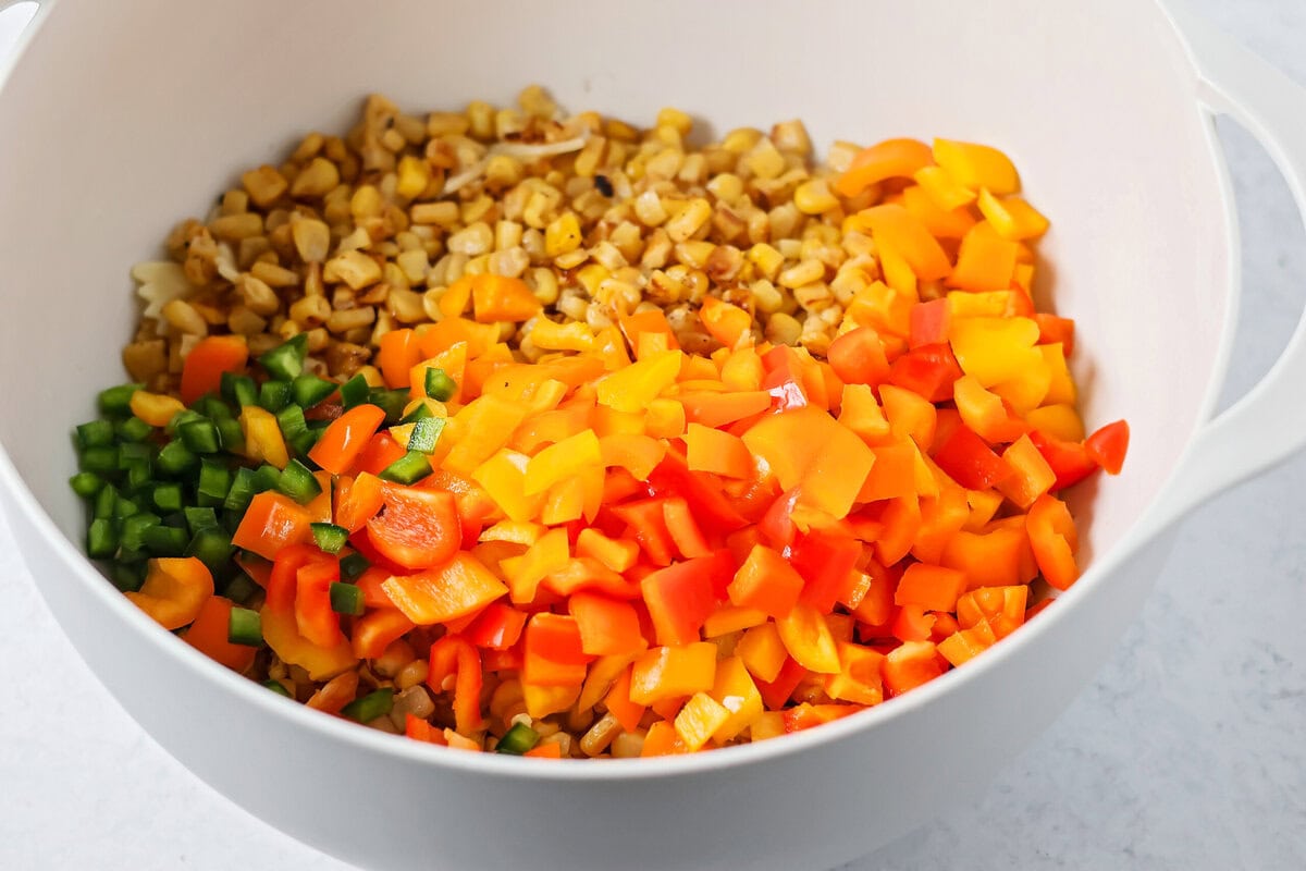 Creamy Mexican street corn pasta salad is a perfect balance of flavor, quick to toss together, and perfect for parties and easy dinners. Roasted corn and sliced veggies in a mixing bowl.