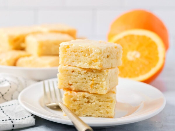 A stack of 3 orange brownies on a plate.