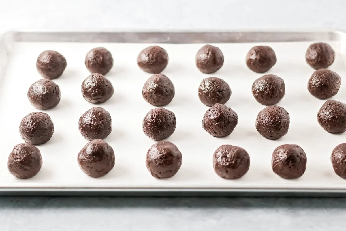 No-bake Oreo cream cheese balls are a three ingredient treat with a silky center and chocolate coating, ideal for every occasion. Chocolate dough balls on a parchment lined baking sheet.