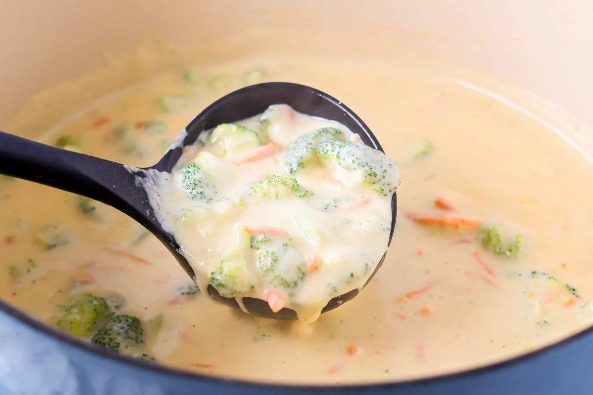 This flavorful Panera broccoli cheddar soup recipe tastes just like the original. Filled with hearty ingredients, it's sure to be a hit! Lifting Panera broccoli cheese soup up with a ladle.