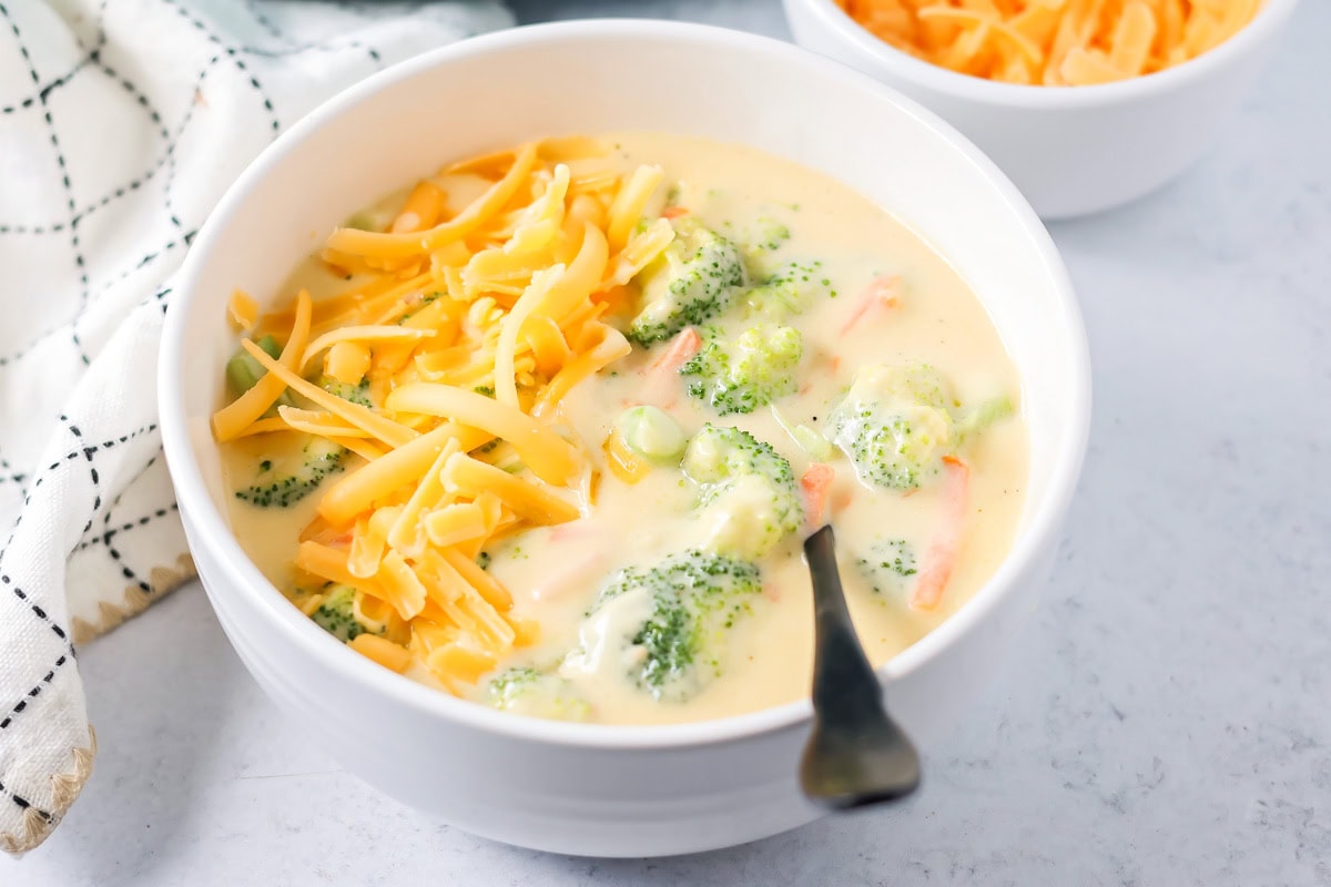 This flavorful Panera broccoli cheddar soup recipe tastes just like the original. Filled with hearty ingredients, it's sure to be a hit! A bowl of our Panera Broccoli Cheddar soup recipe topped with shredded cheese.
