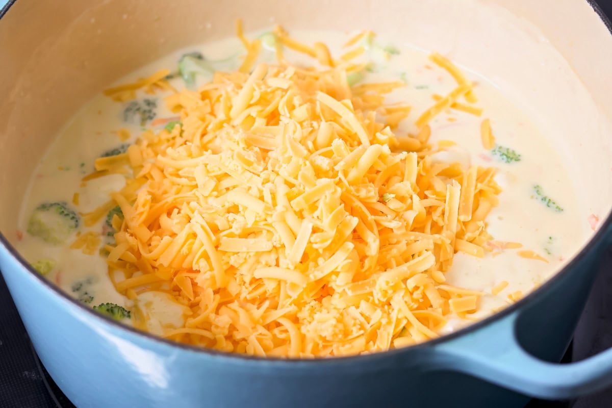 This flavorful Panera broccoli cheddar soup recipe tastes just like the original. Filled with hearty ingredients, it's sure to be a hit! Adding shredded cheese to the soup.