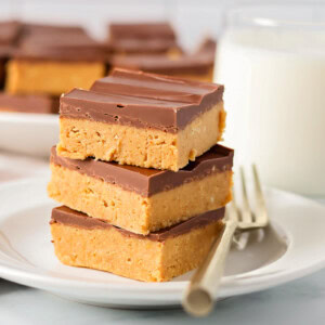 Peanut butter bars stacked on top of each other on white plate.