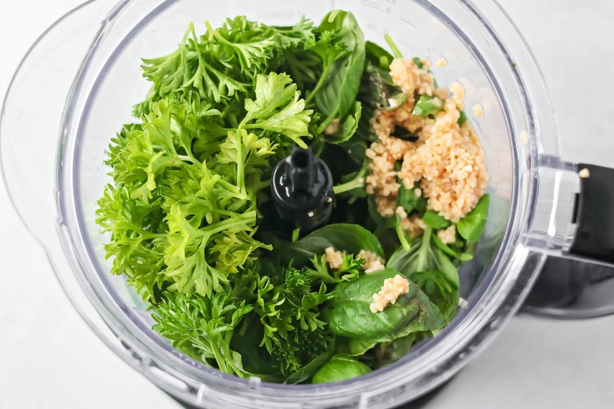 Fresh homemade basil pesto is easy and quick to make. From pasta to sandwiches, it will be a family favorite you use all week! Basil, parsley, and garlic in a food processor.