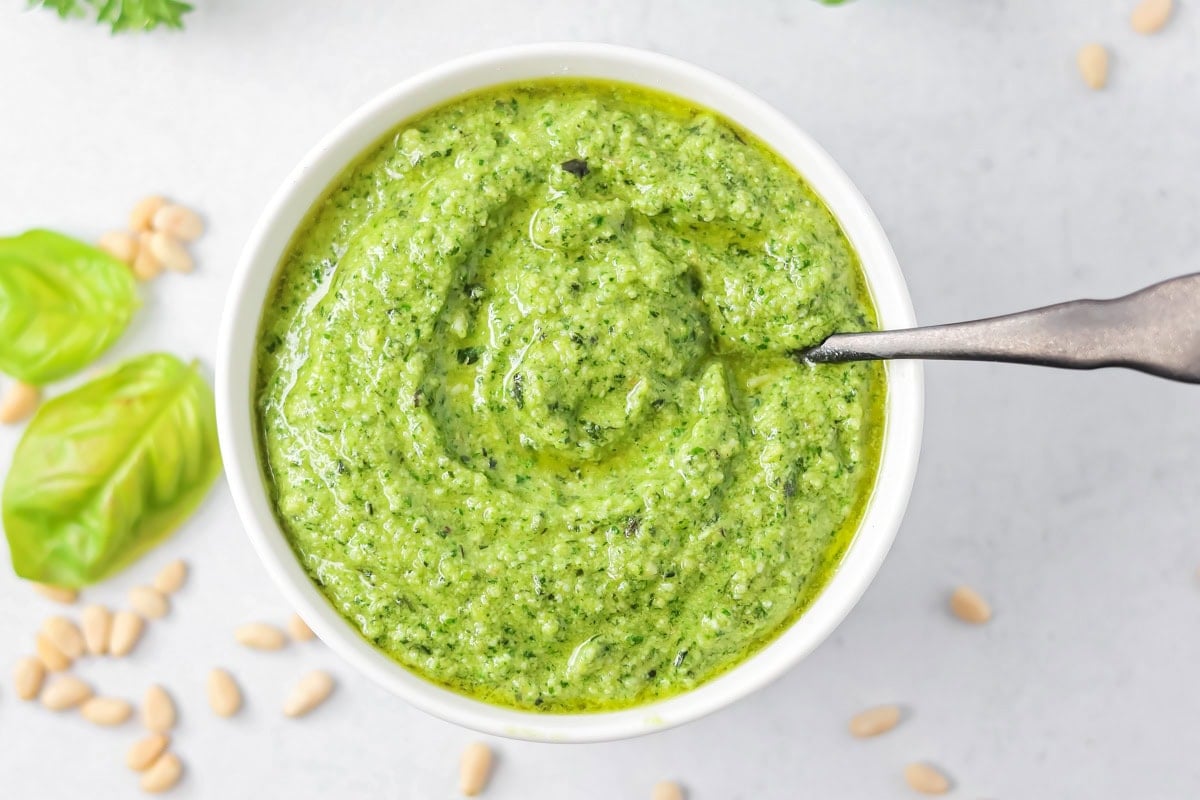 Fresh homemade basil pesto is easy and quick to make. From pasta to sandwiches, it will be a family favorite you use all week! A bowl of basil pesto with a serving spoon.