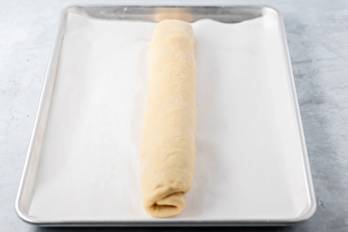 Quick cinnamon twists are made with a simple soft, buttery dough, and swirled with cinnamon sugar and are perfect for breakfast or dessert. Rolled log of dough on a parchment paper lined baking sheet.