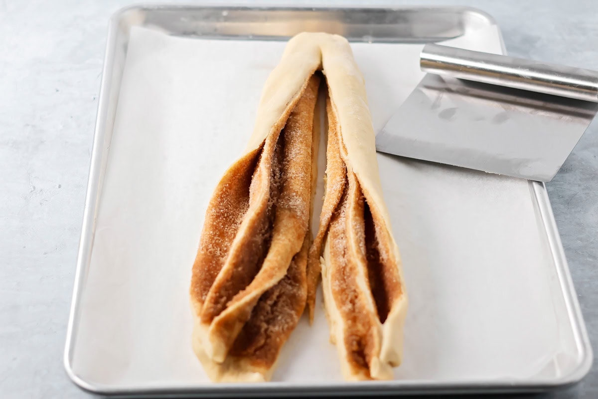 Quick cinnamon twists are made with a simple soft, buttery dough, and swirled with cinnamon sugar and are perfect for breakfast or dessert. A rolled log of dough cut in half lengthwise to expose cinnamon center.