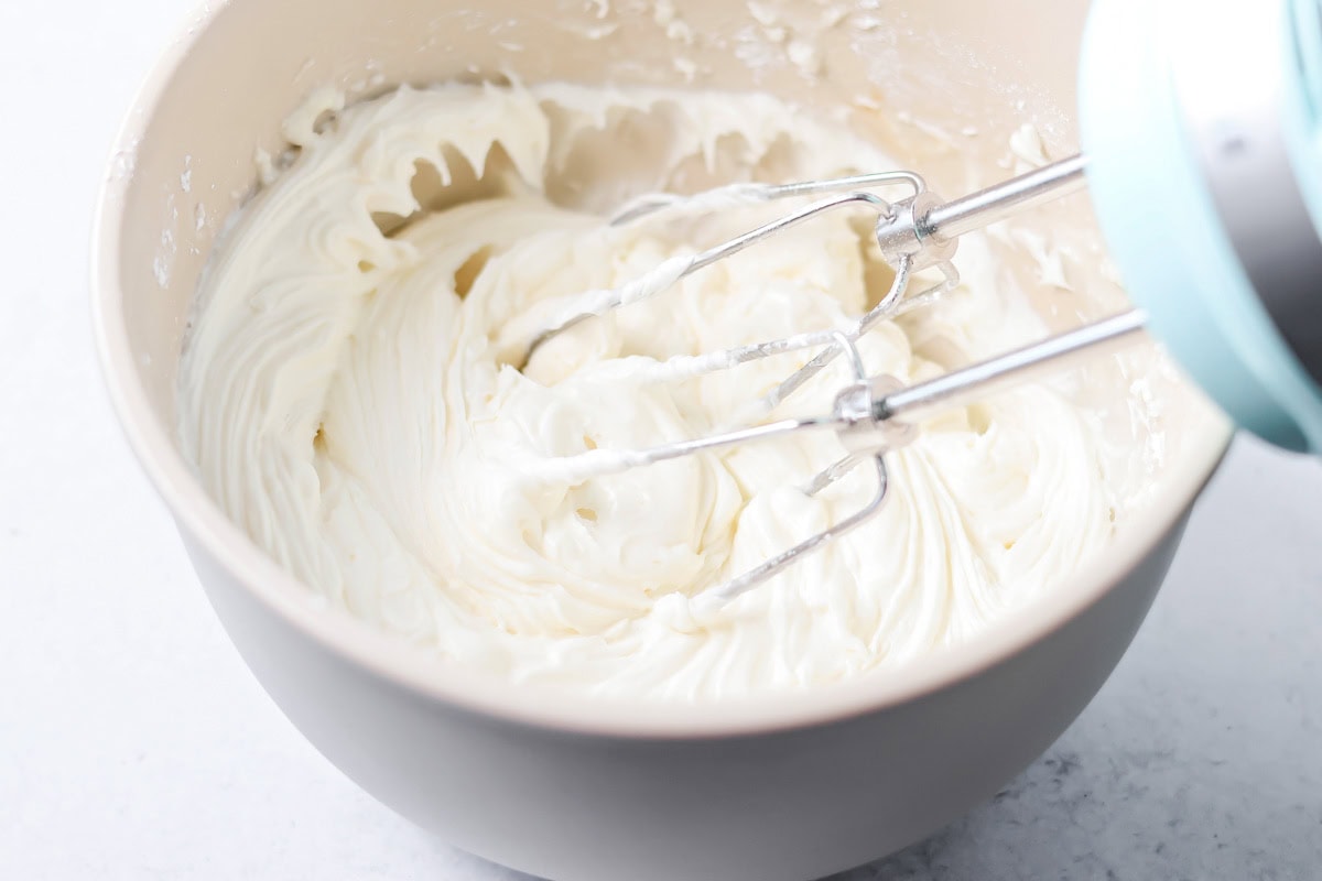 Quick cinnamon twists are made with a simple soft, buttery dough, and swirled with cinnamon sugar and are perfect for breakfast or dessert. Mixing vanilla frosting in a bowl.