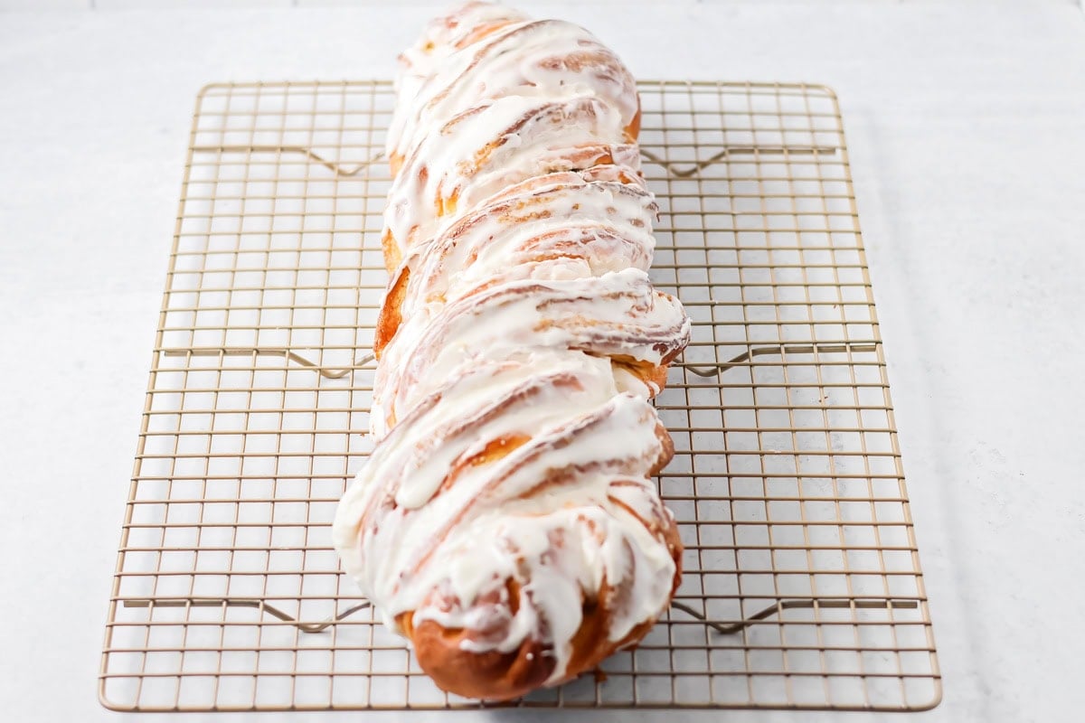 Quick cinnamon twists are made with a simple soft, buttery dough, and swirled with cinnamon sugar and are perfect for breakfast or dessert. Frosted cinnamon twist on a cooling rack.