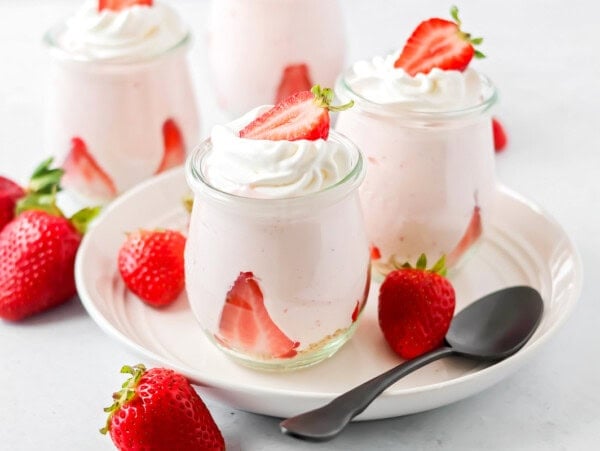 Strawberry mousse in glass jars with strawberries on top.