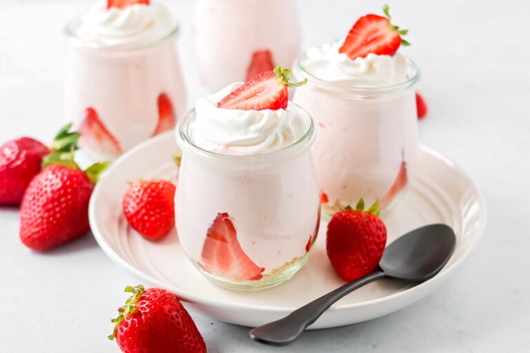 Strawberry mousse in glass jars with strawberries on top.