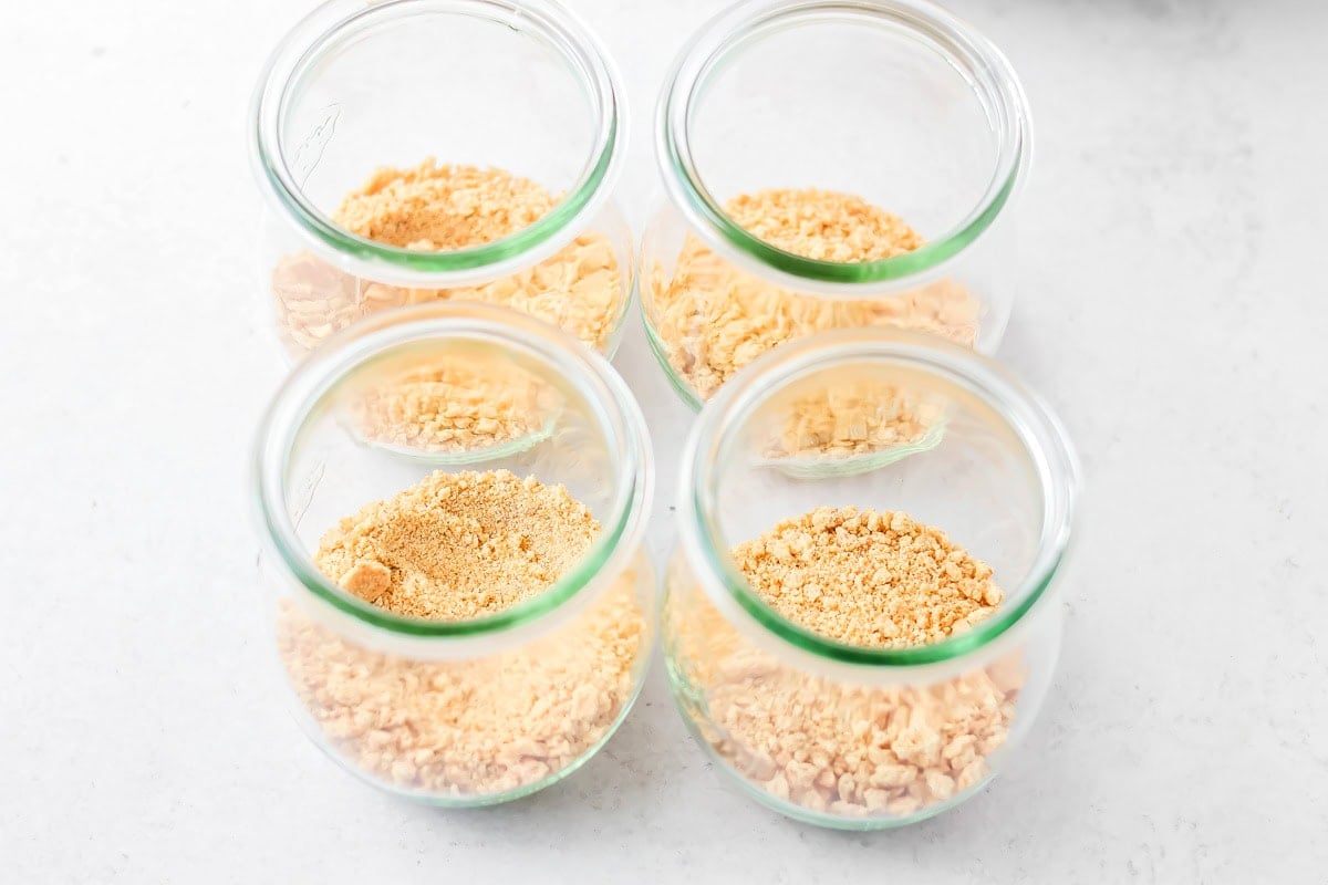 Graham cracker crumbs in bottom of glass jar.