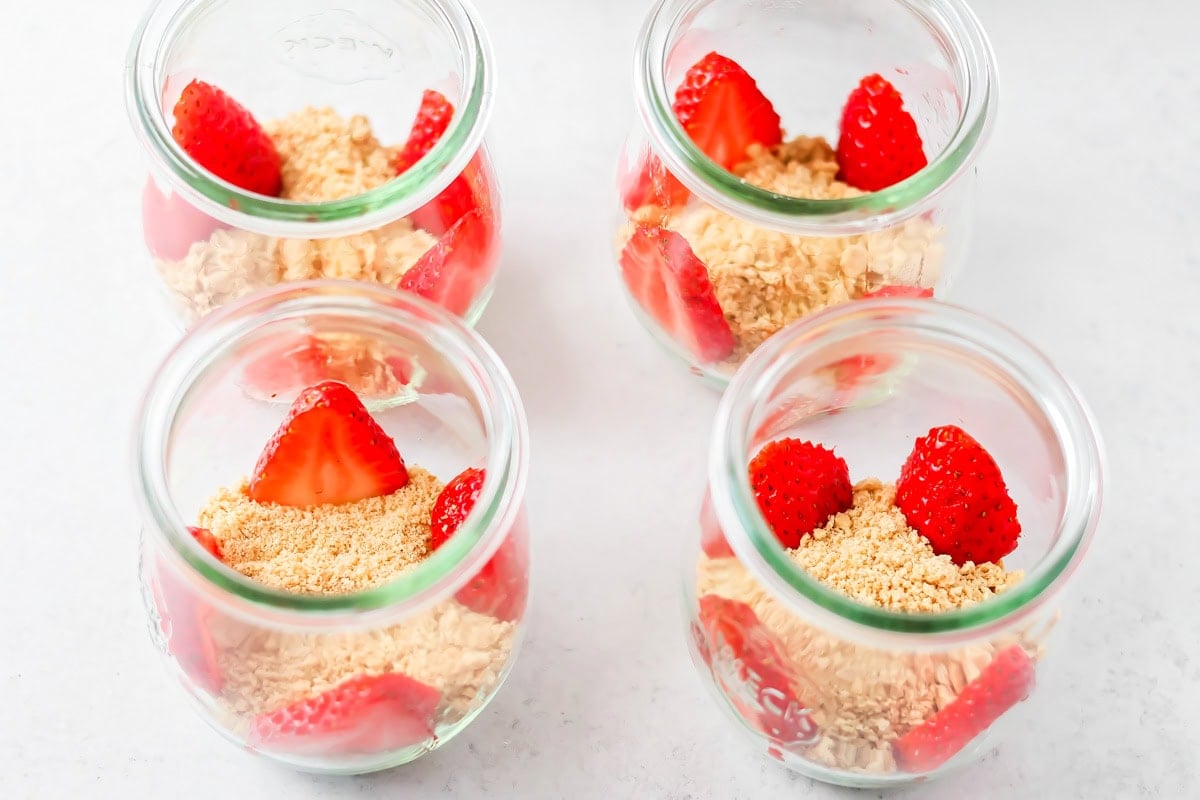 Strawberries on the sides of glass jars for strawberry mousse recipe.