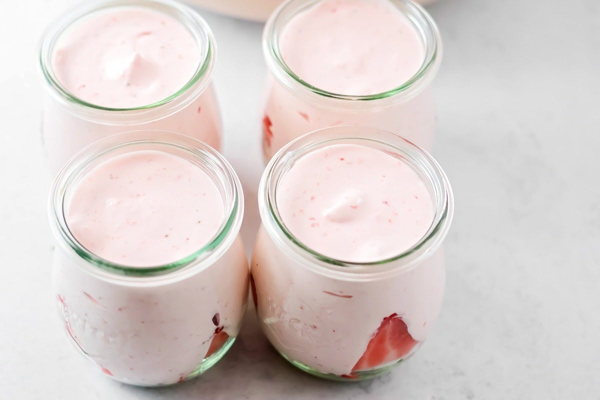 Mousse filled to the top of glass jar with strawberries in it.