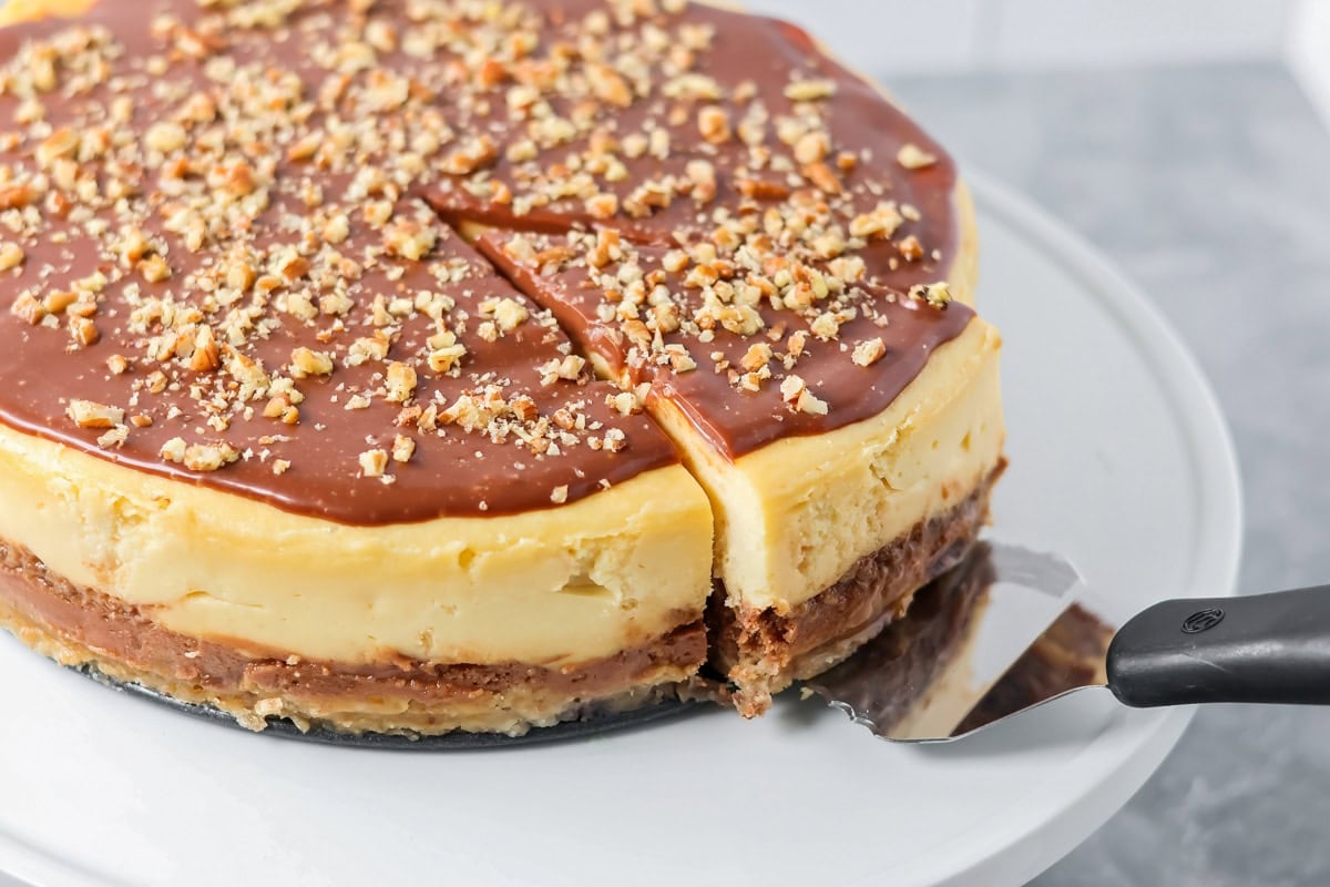 A slice of cheesecake being removed with a pie server.