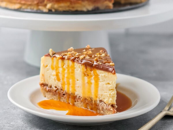 Slice of turtle cheesecake served on a white plate.